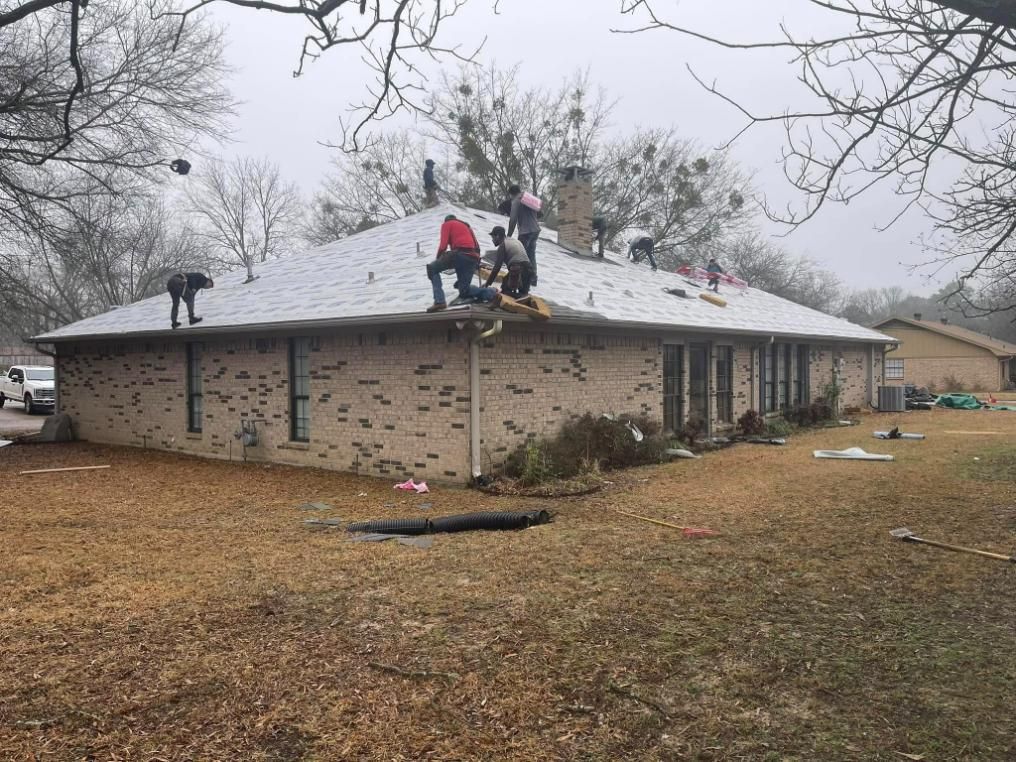 Roofers working on a brick home's roof on a cloudy day.