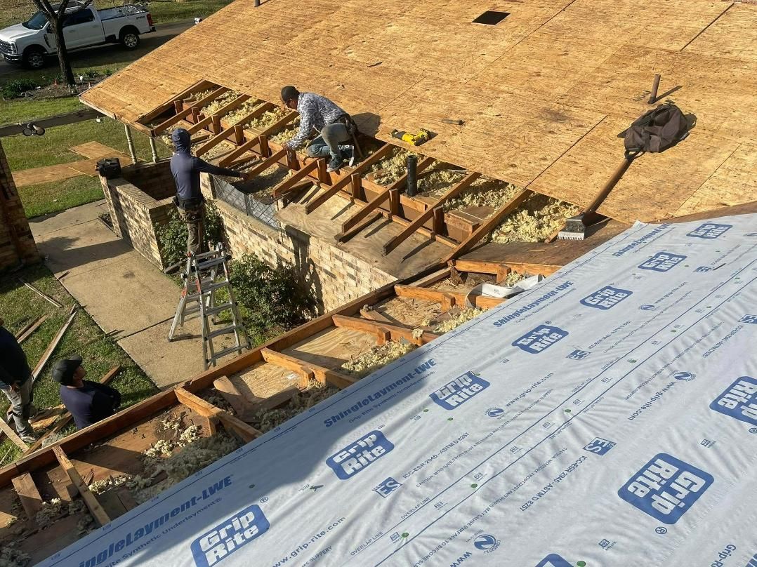 Roofers working on a house roof, replacing wood framing, insulation, and sheathing.