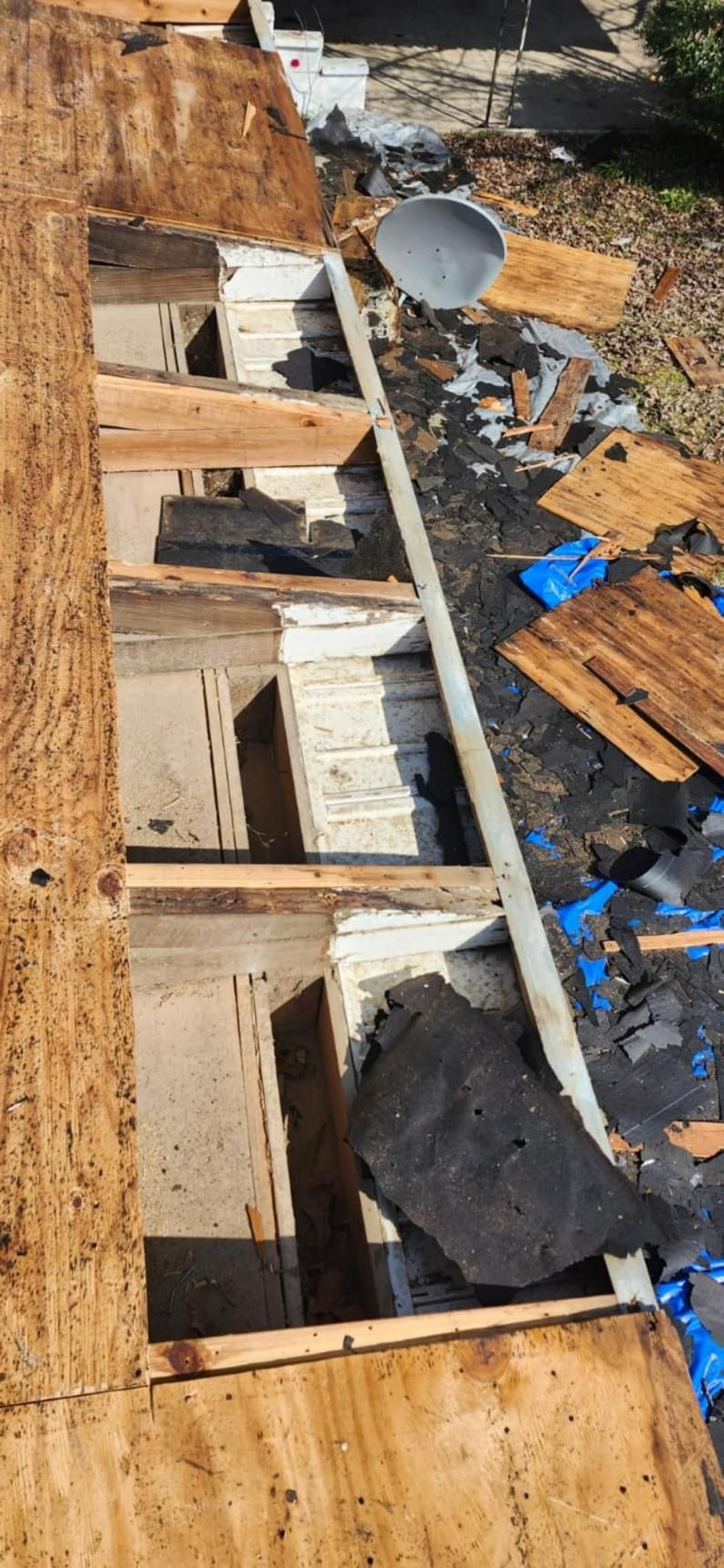 Roof under construction; exposed wood, insulation, debris, and a satellite dish.