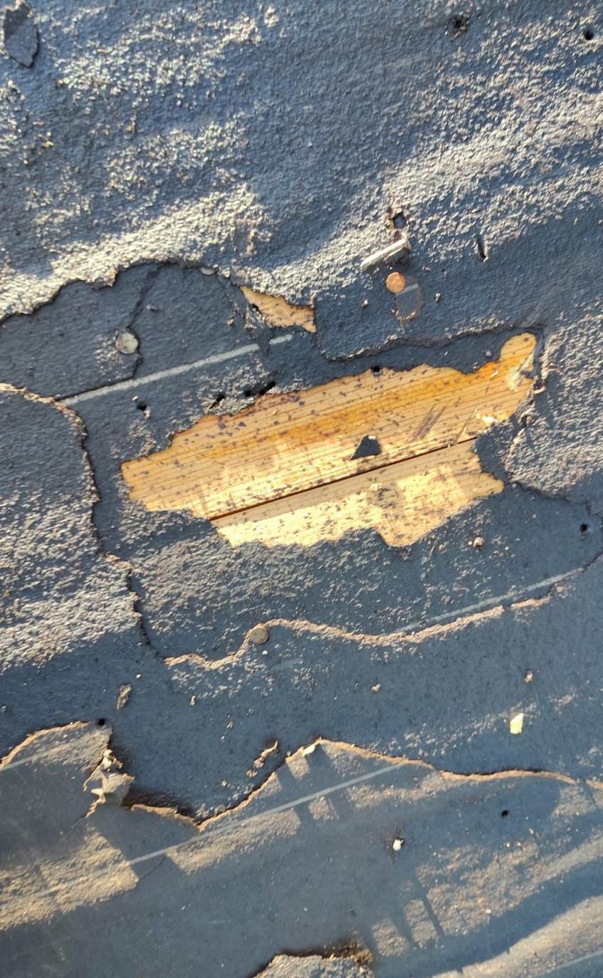 Cracked, peeling gray surface revealing a tan/yellow layer underneath, with light and shadow.