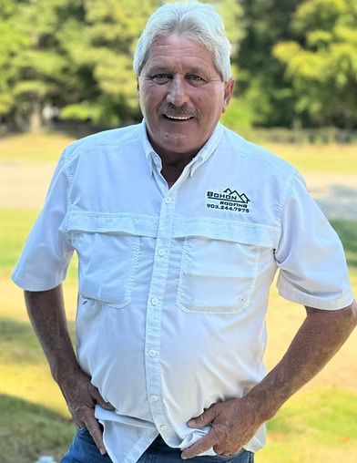 Man in white shirt with hands on hips smiling outdoors.