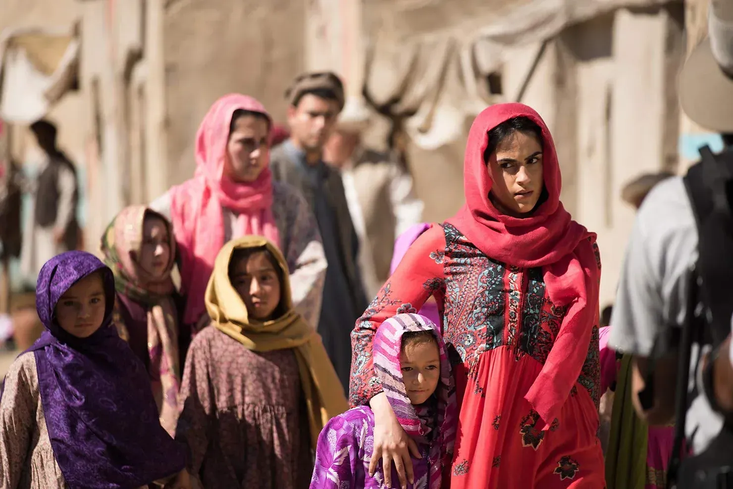 A woman in a red dress is standing with her family in a crowd of people.