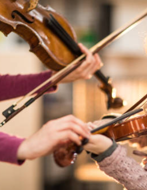 violin teacher guiding student's hands on their violin