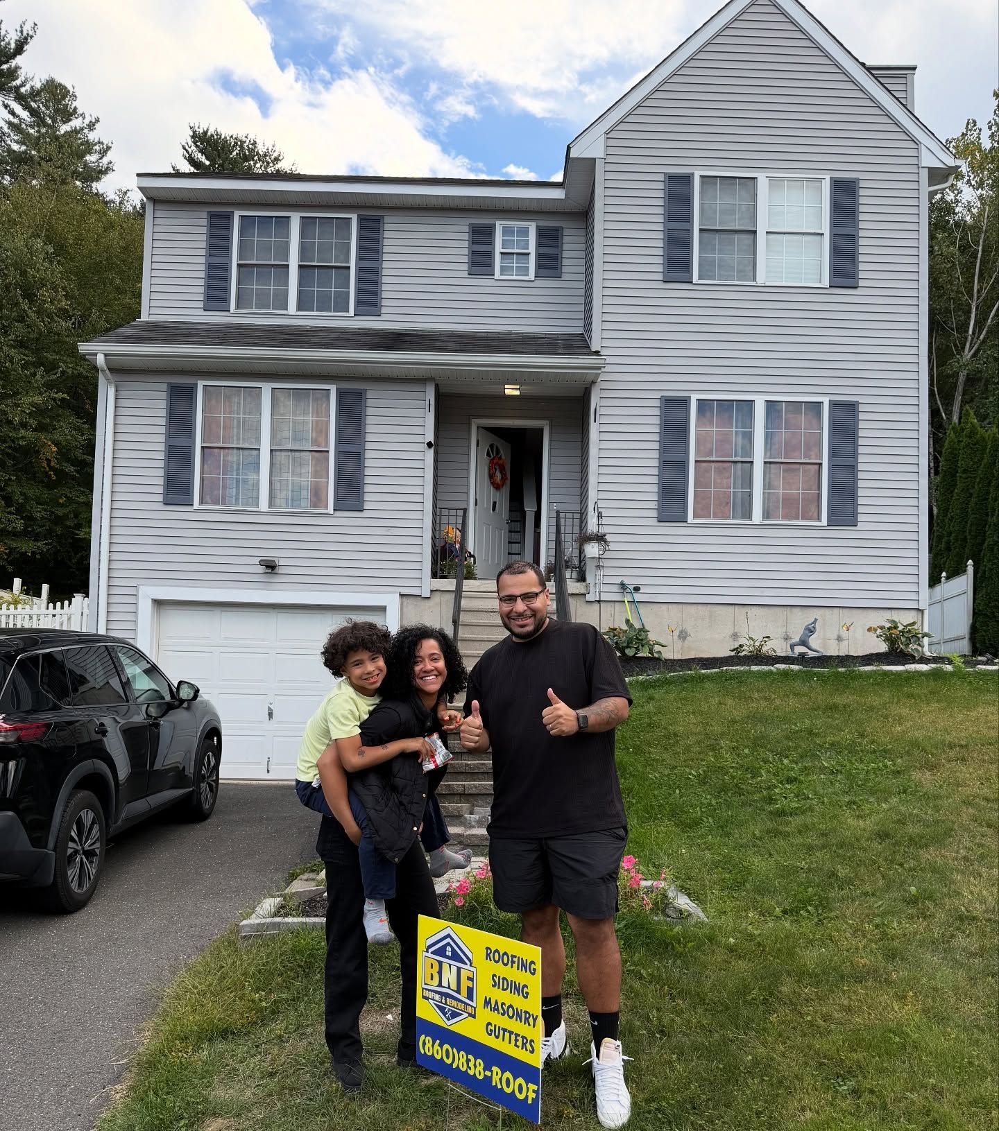 Family in front of a two-story house, celebrating. A sign says 