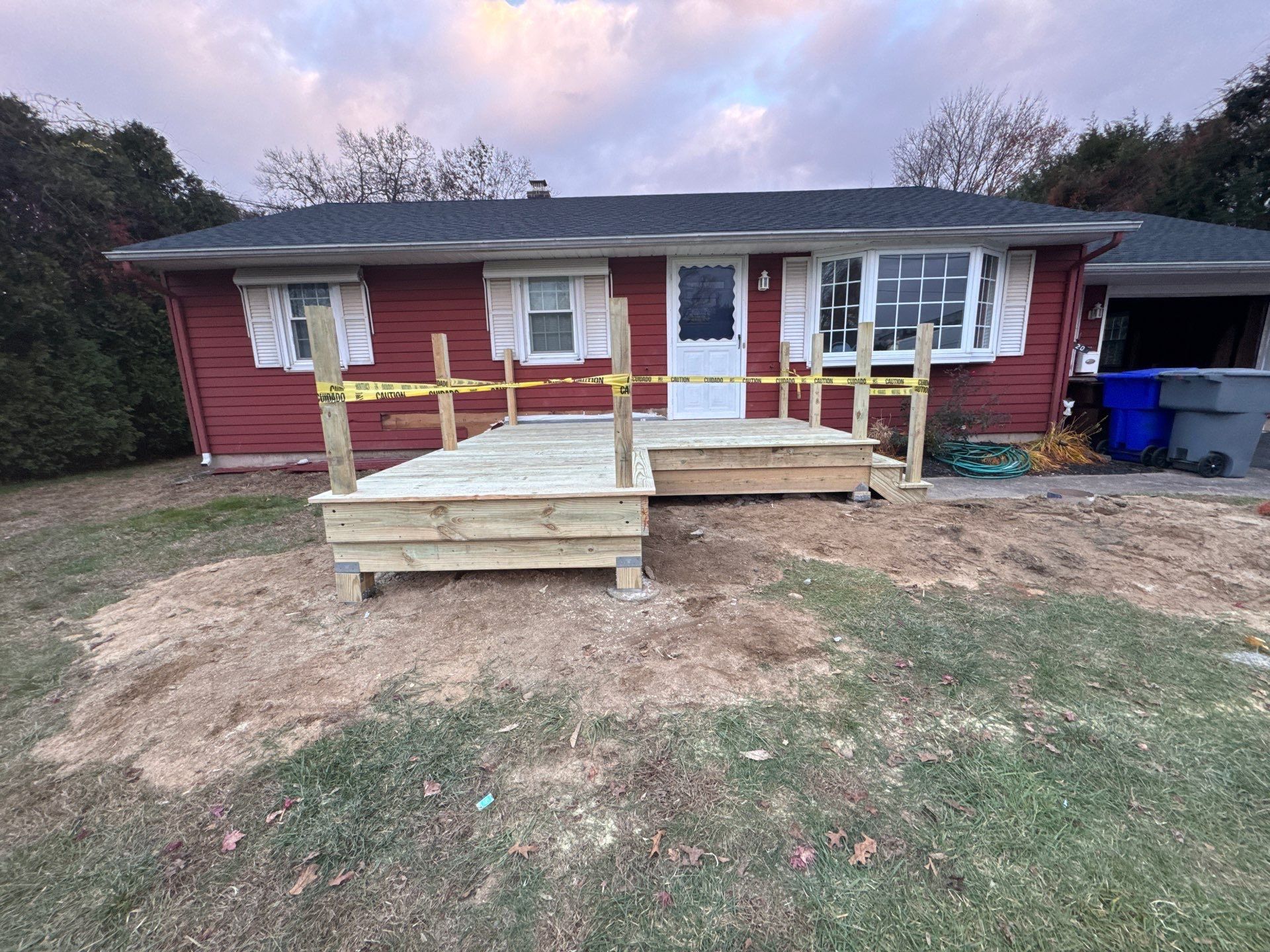 Red house with new wooden deck, caution tape across railings.