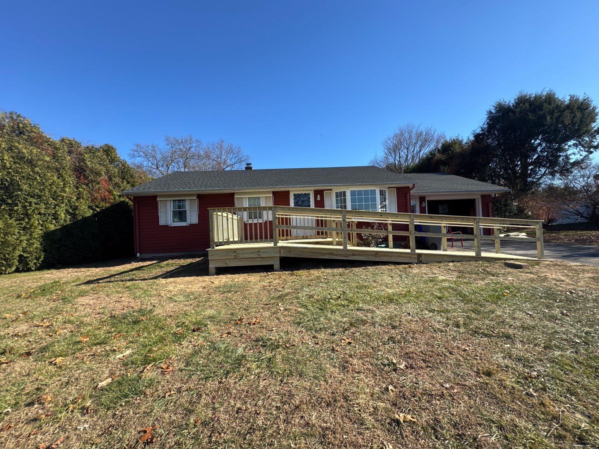 Red house with wooden ramp and deck; blue sky overhead.