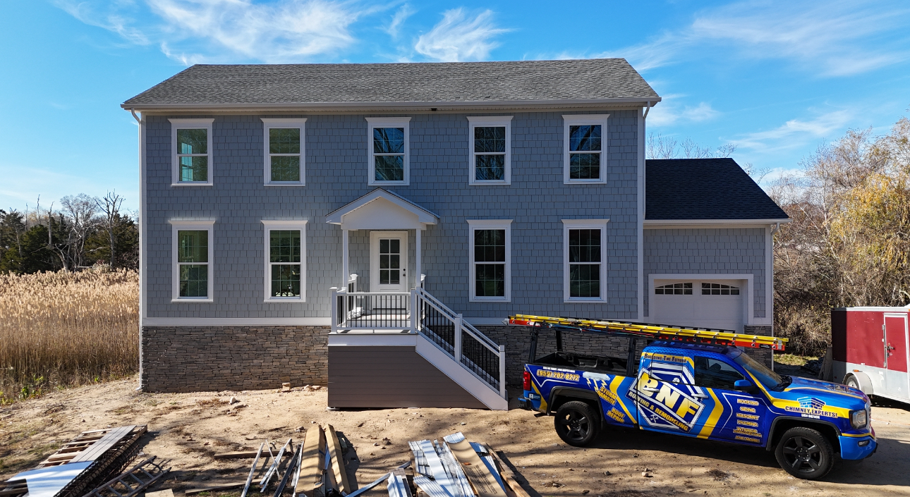 Two-story light blue house with a gray roof and a blue truck parked in front.