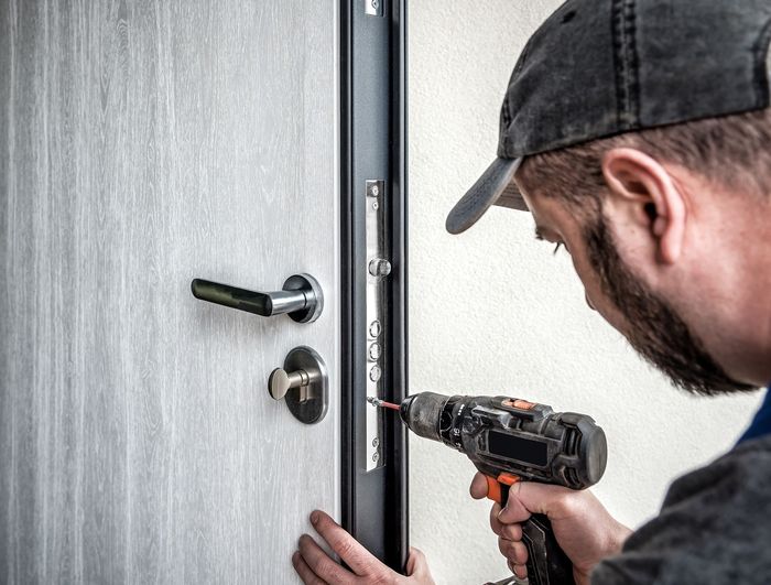 A man is fixing a door with a drill.