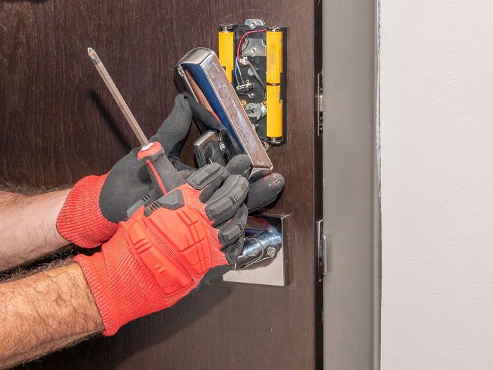 A man is fixing a door lock with a screwdriver.