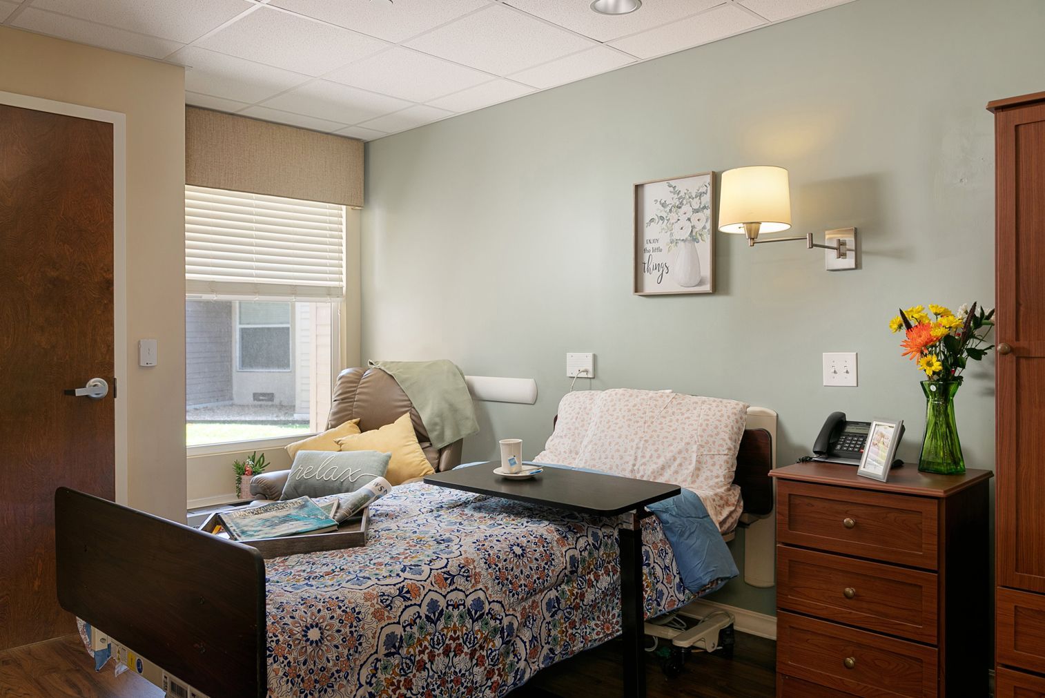 A bedroom with a bed , dresser , nightstand and window.