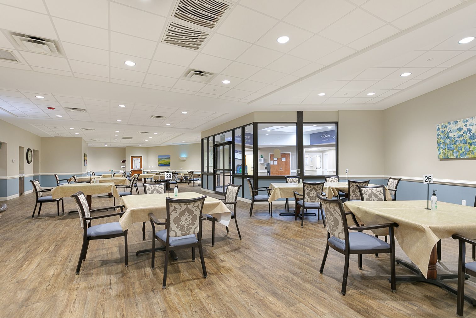 A large dining room with tables and chairs in a nursing home.