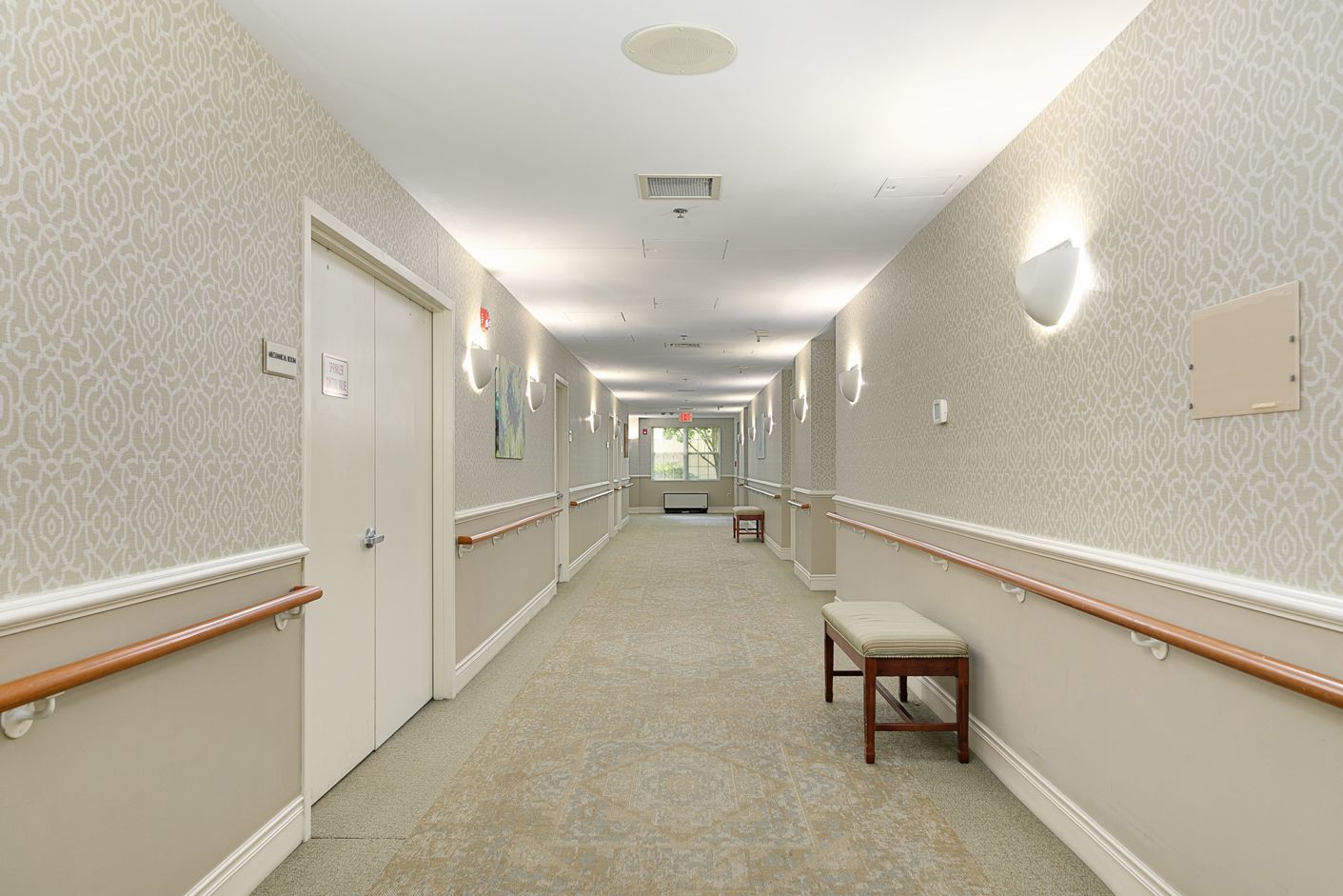 A long hallway with a bench in the middle of it.