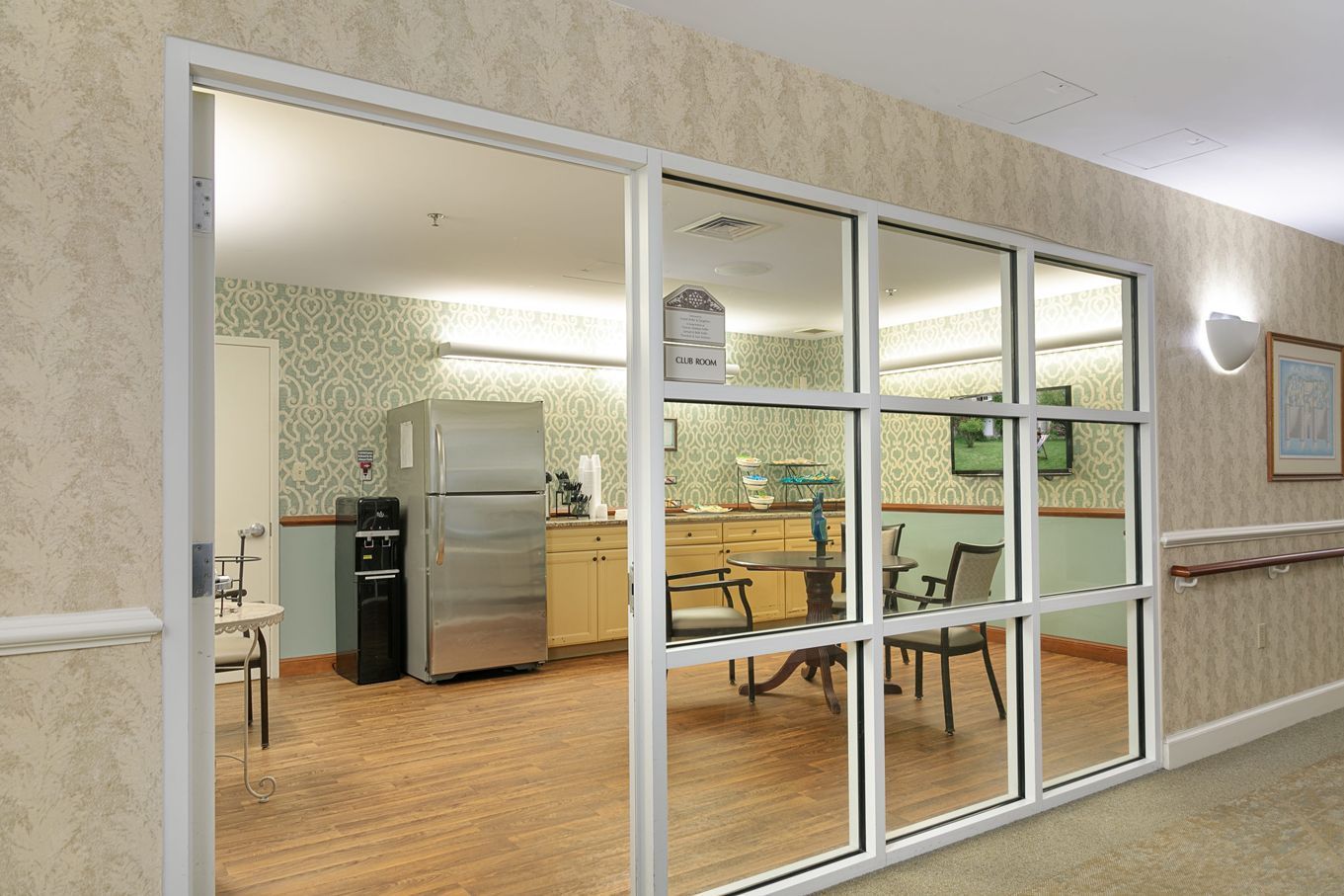 A room with a refrigerator and a table and chairs in it