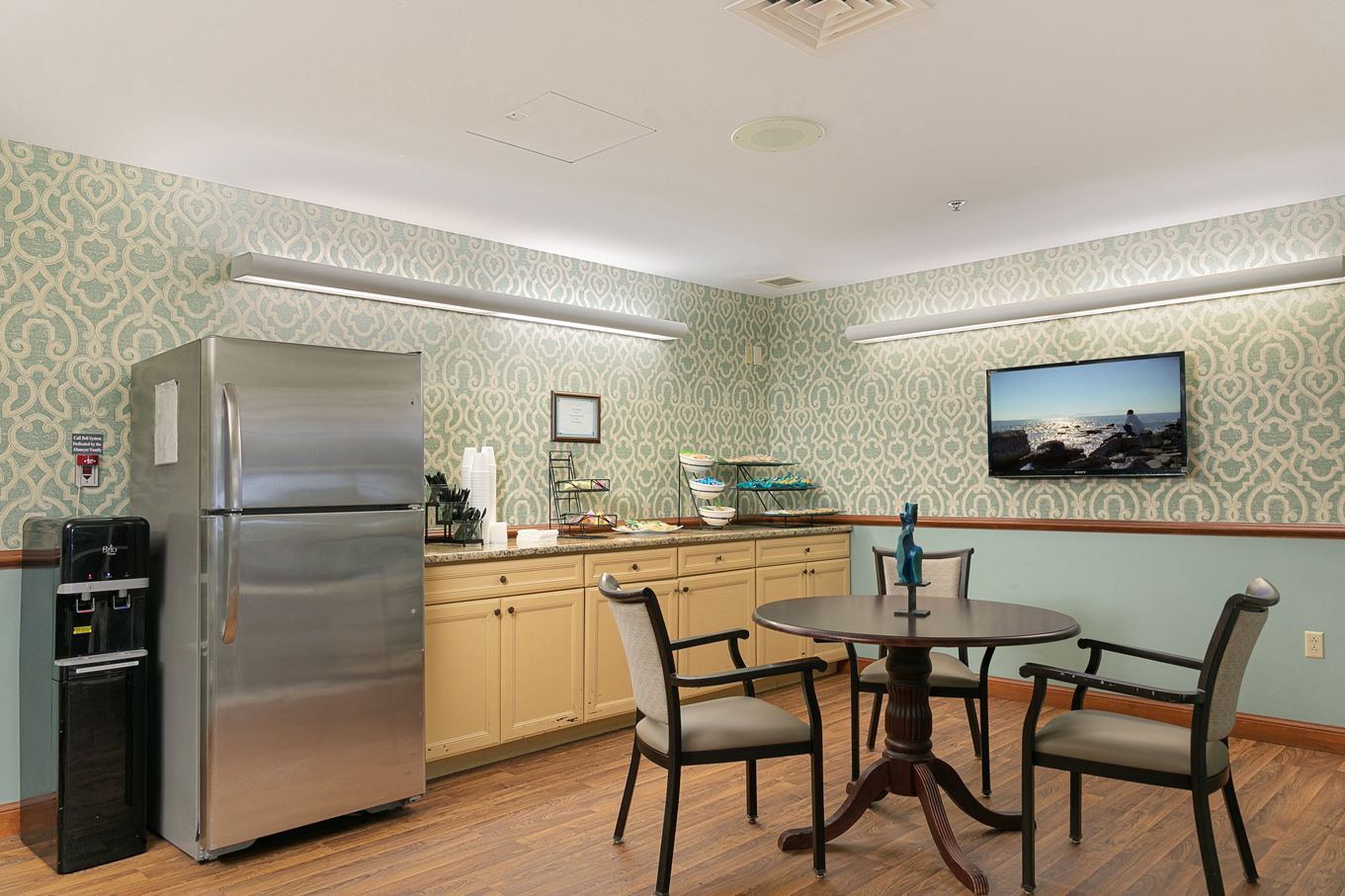 A kitchen with a table , chairs , refrigerator and television.