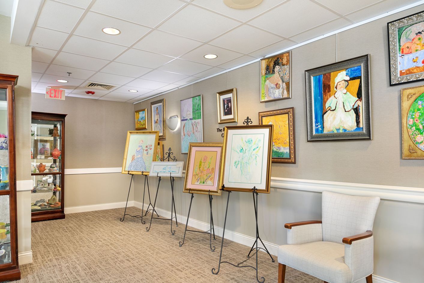 A room with a lot of paintings on the wall and a chair.