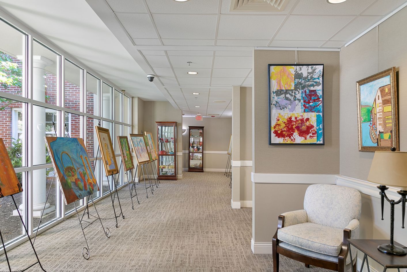 A hallway with paintings on easels and a chair.