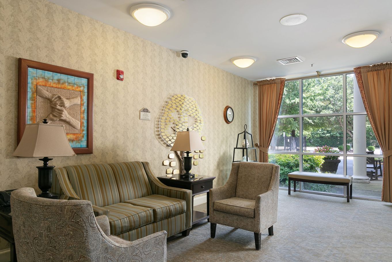 A living room with a couch , chairs , lamps and a large window.