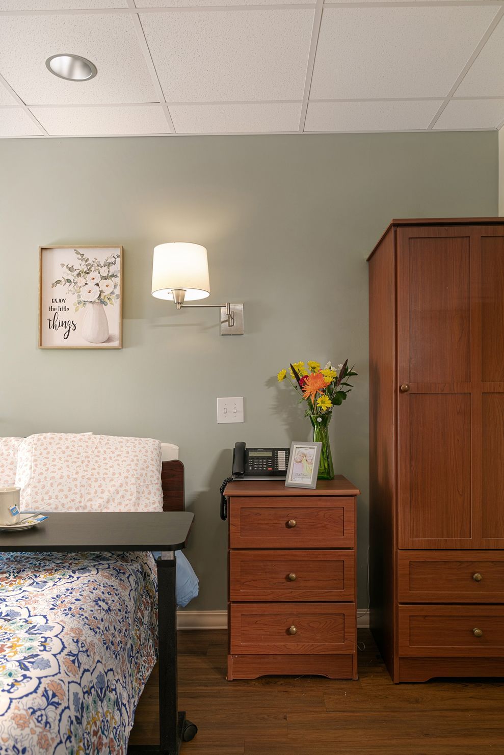 A bedroom with a bed , nightstand , dresser and a picture on the wall.