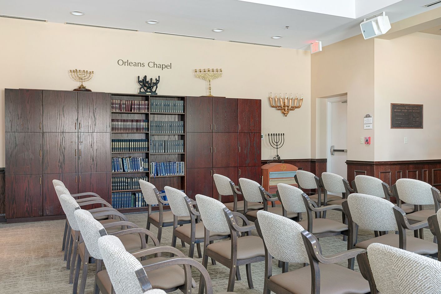 A room with rows of chairs and a bookshelf with books on it
