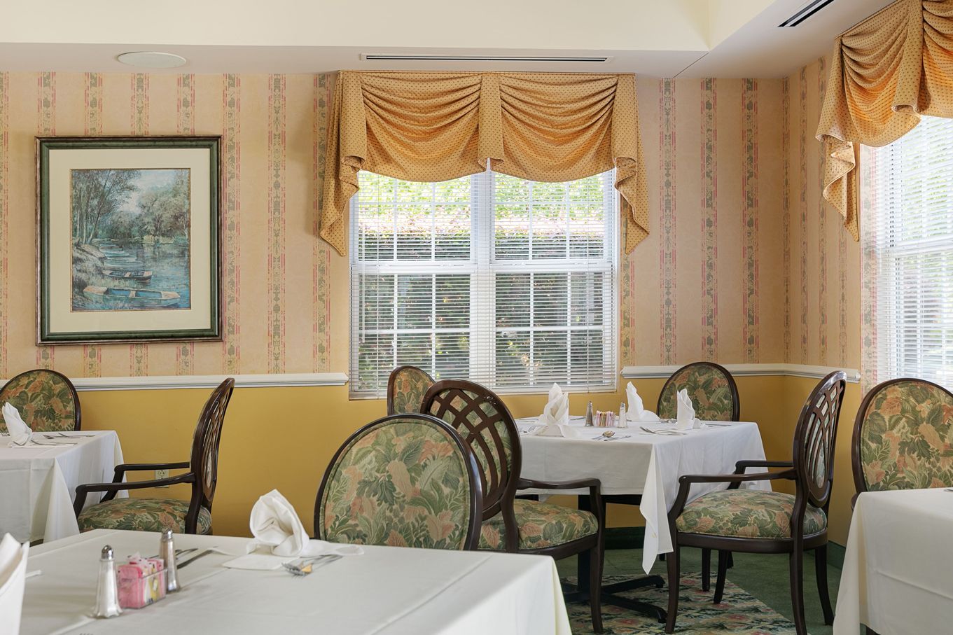 A dining room with tables and chairs and a picture on the wall.