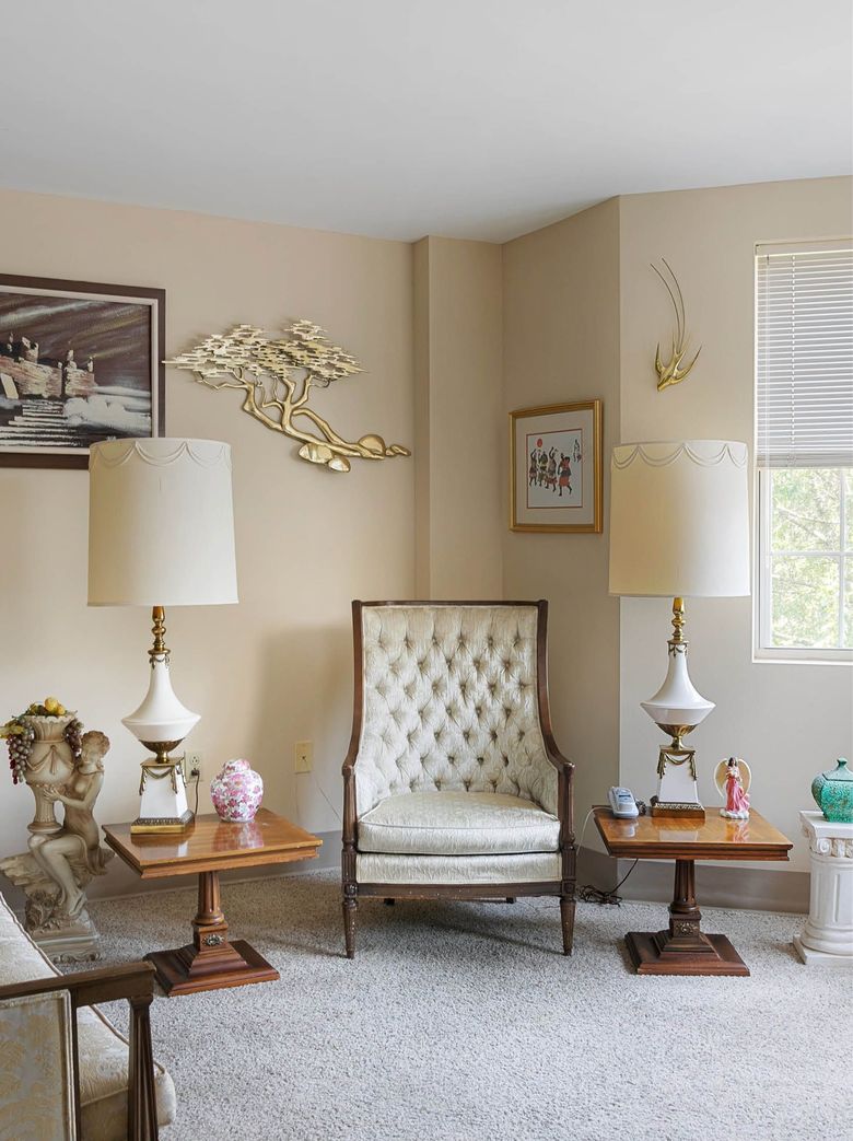 A living room with a chair , two lamps , two tables and a window.