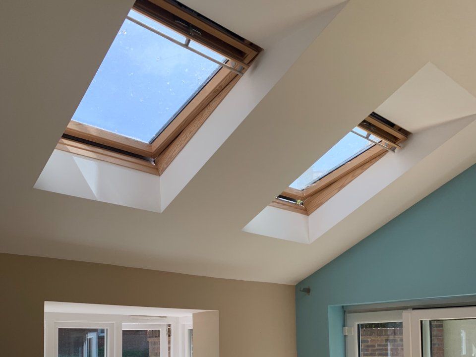 Picture of loft ceiling painted white around two Velux windows and light turquoise feature wall painted by painters and decorators Derby