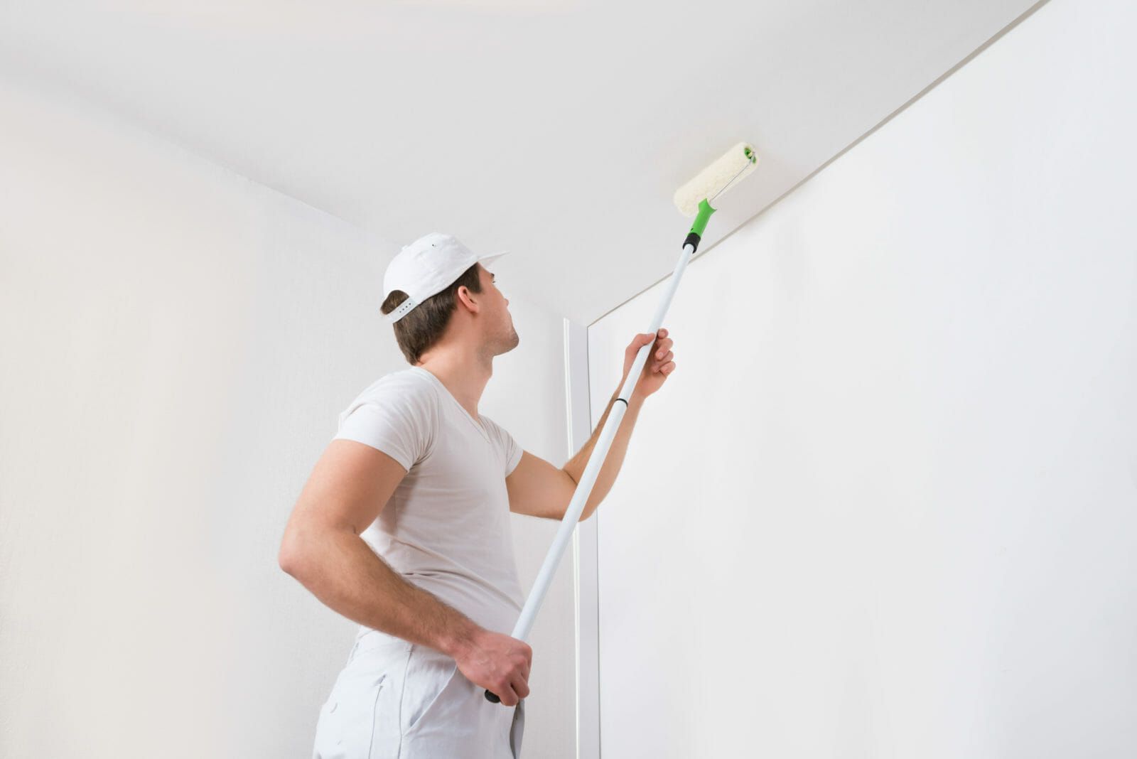 A picture of a painter and decorator painting a ceiling