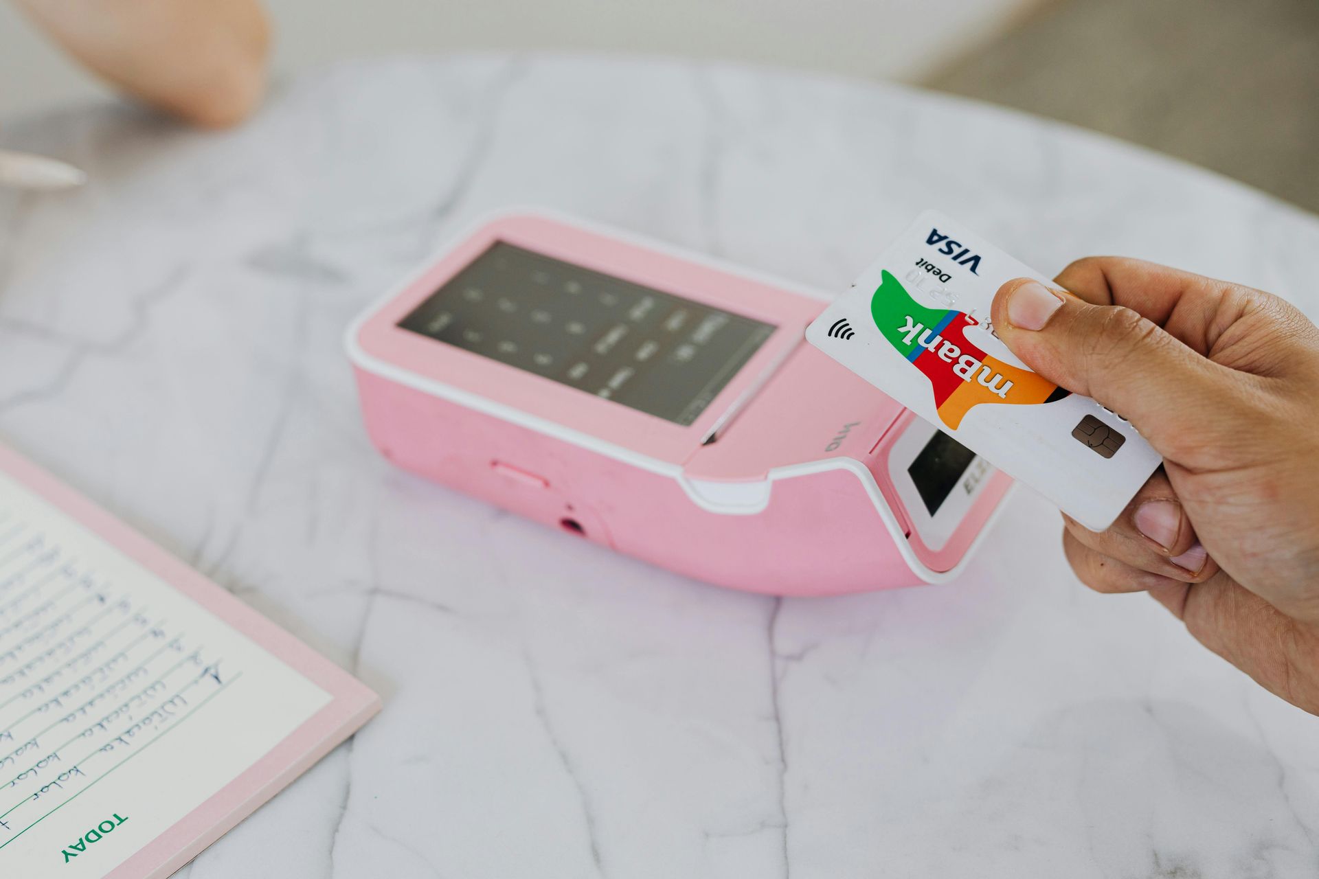 A person is holding a credit card in front of a credit card reader.