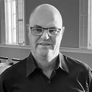 Smiling woman with glasses holding two handbells.