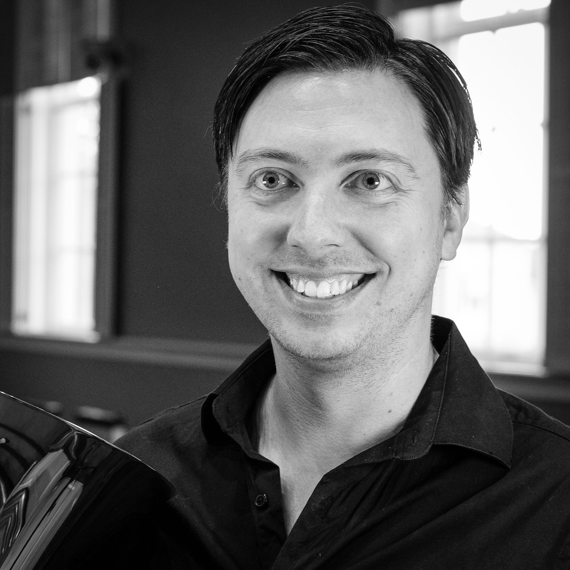 Smiling man, black shirt, indoors, natural light.