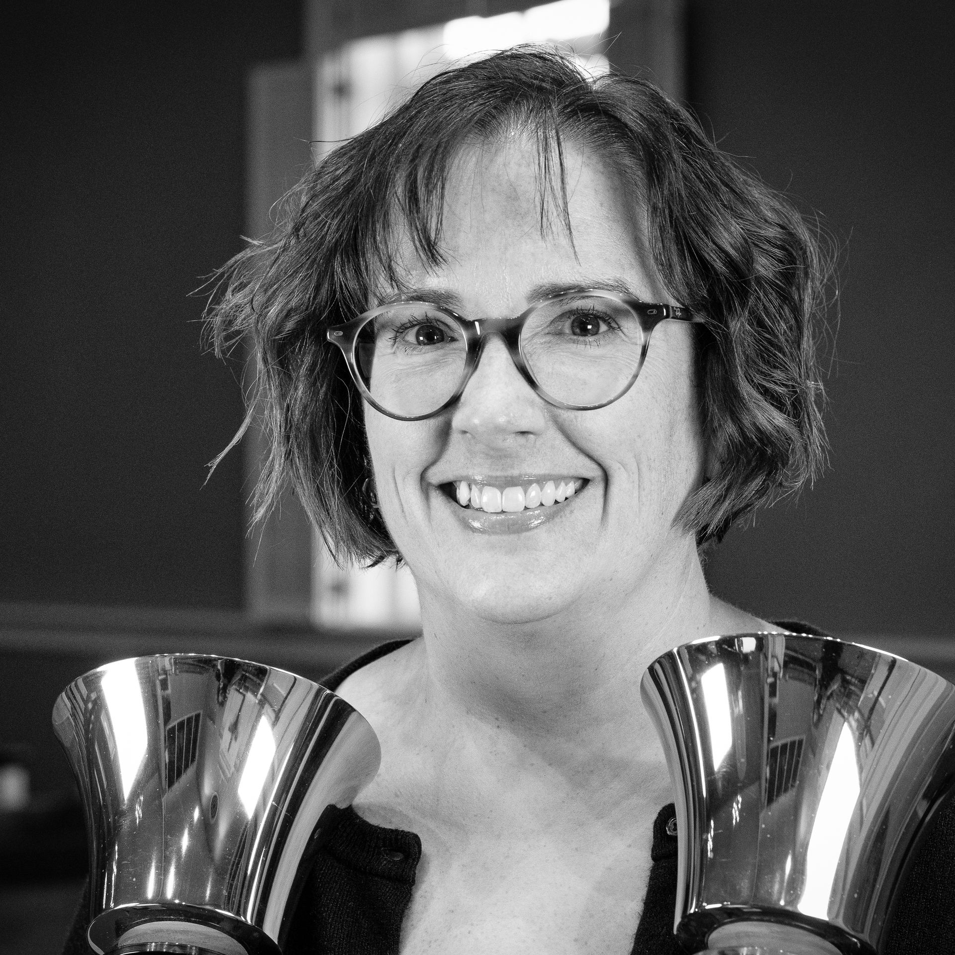 Woman with glasses and bells smiles at the camera.