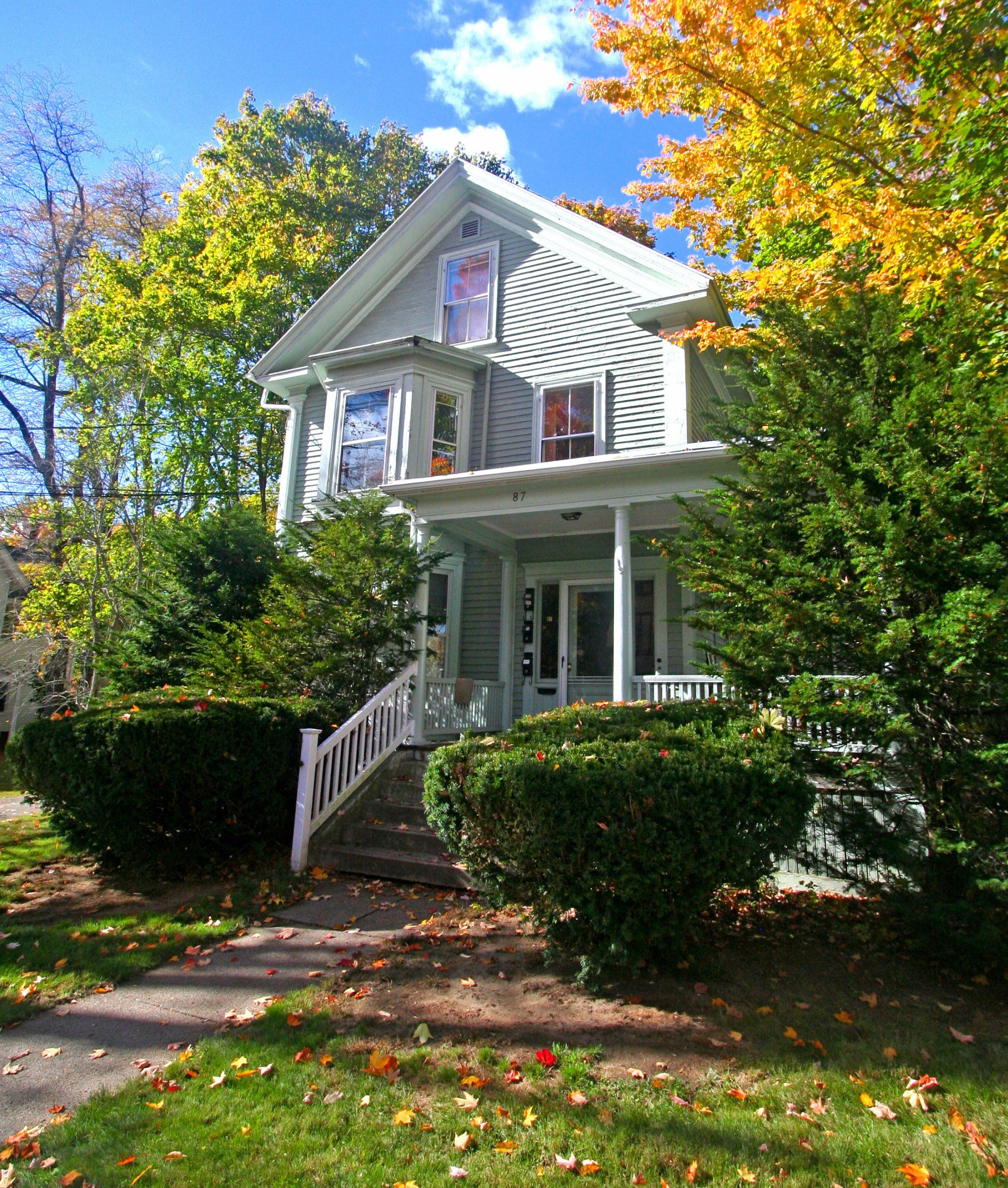 Exterior view of two story grey home with large front yard, stairs to large porch.