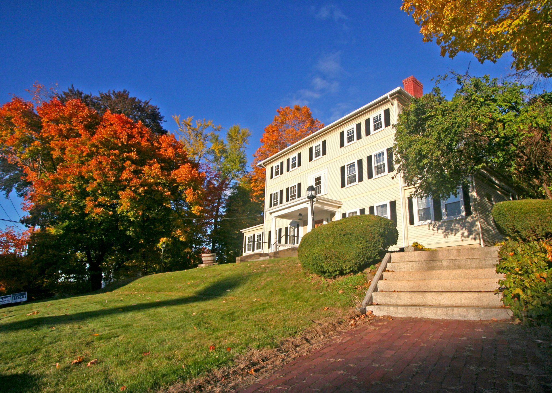 Exterior view of three story beige home large driveway and front yard.