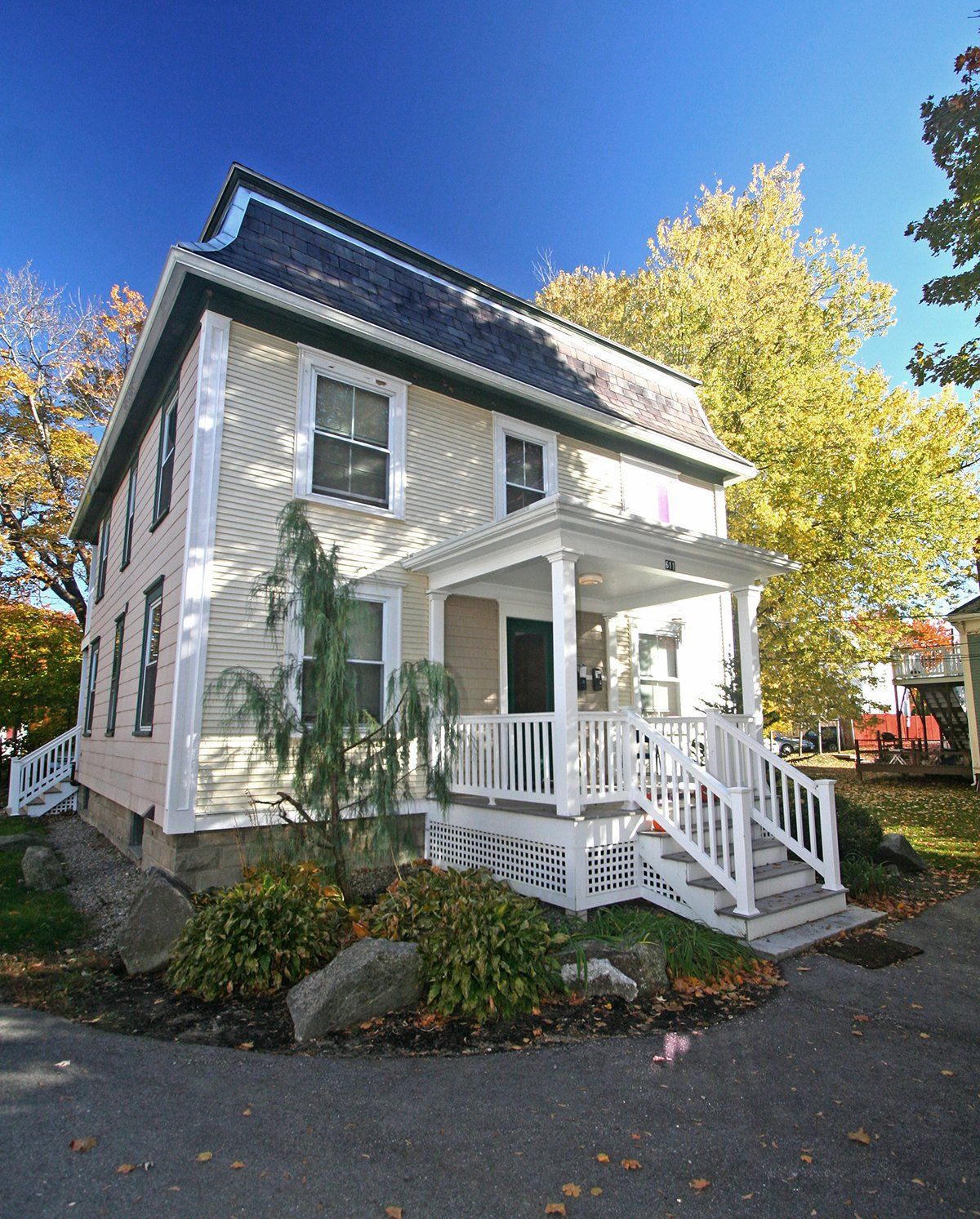 Exterior view of two story beige home with stairs to front porch.