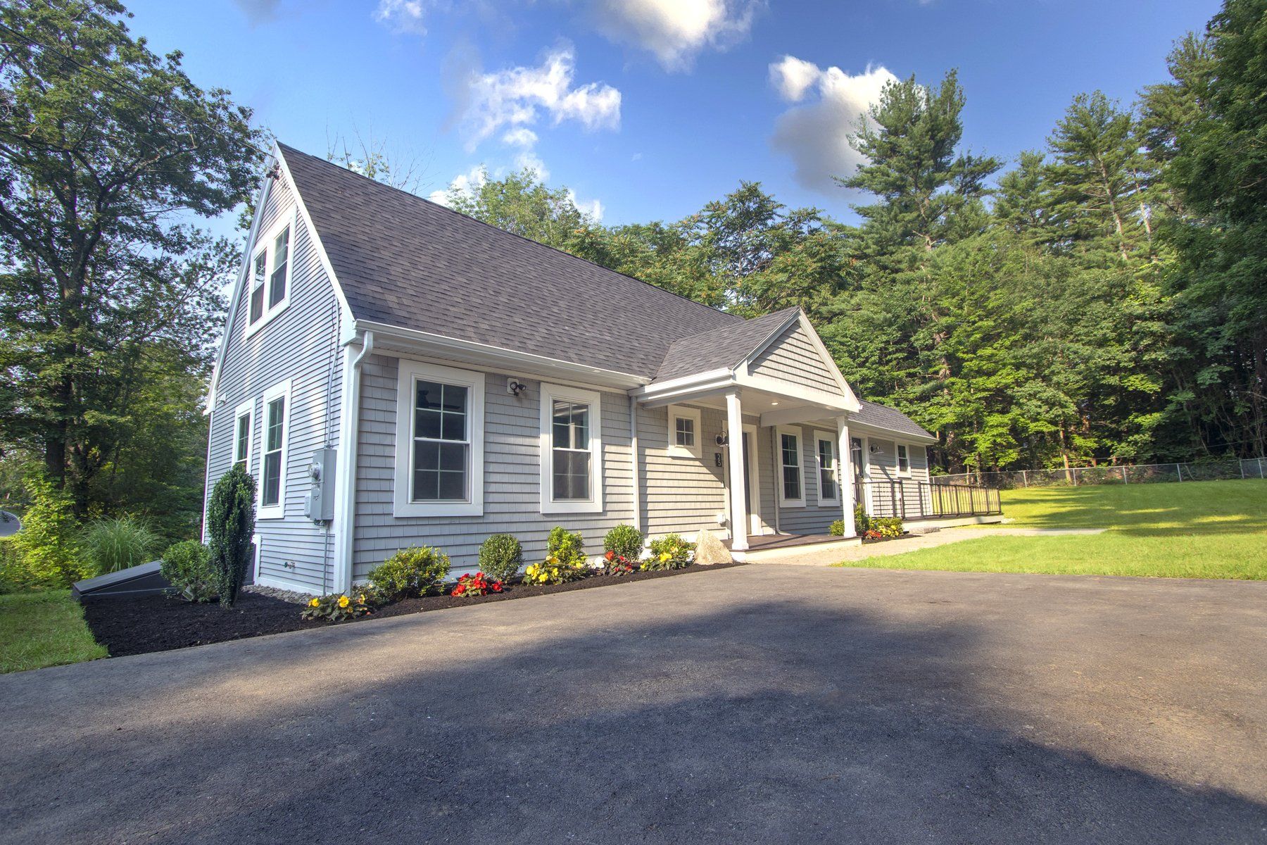 Exterior view of one story grey home large driveway.