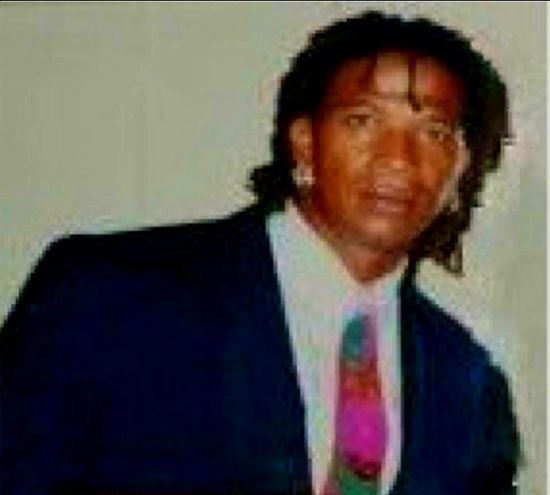 A woman is sitting at a desk with a laptop and a vase of flowers.