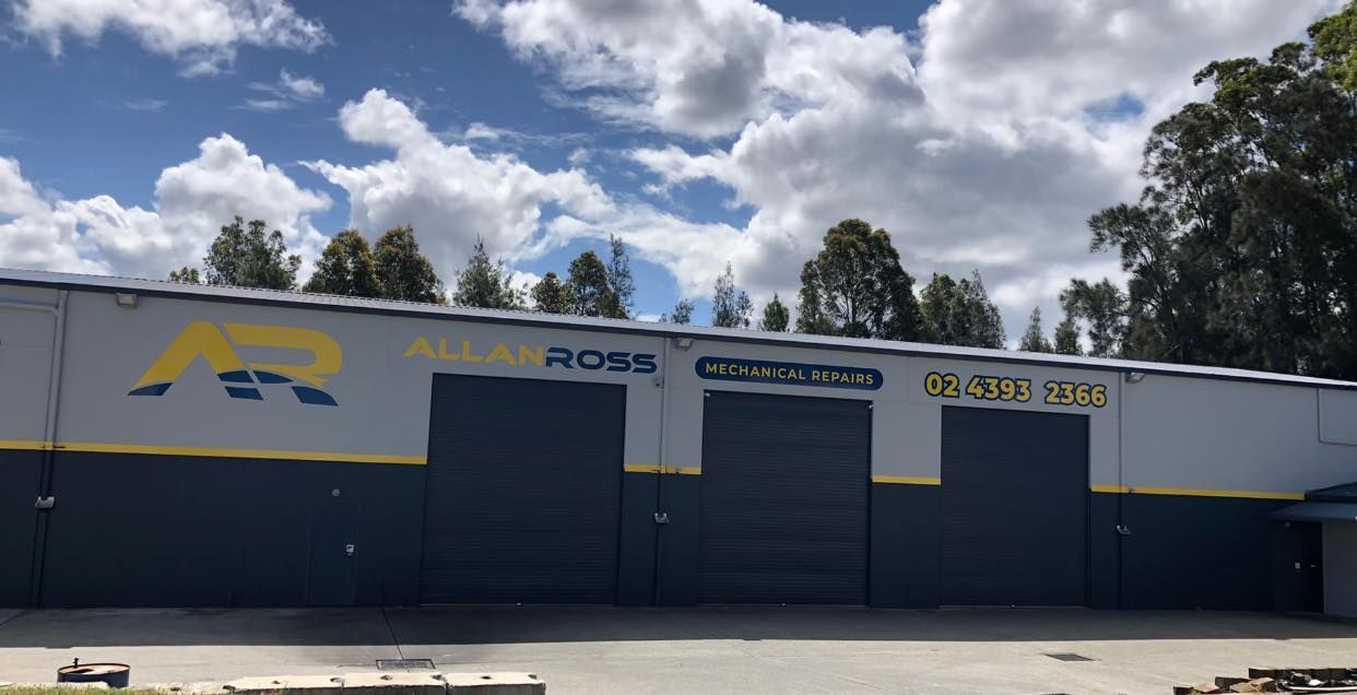 A Man Is Working on The Radiator of A Car in A Garage — Allan Ross Mechanical Repairs in Charmhaven, NSW