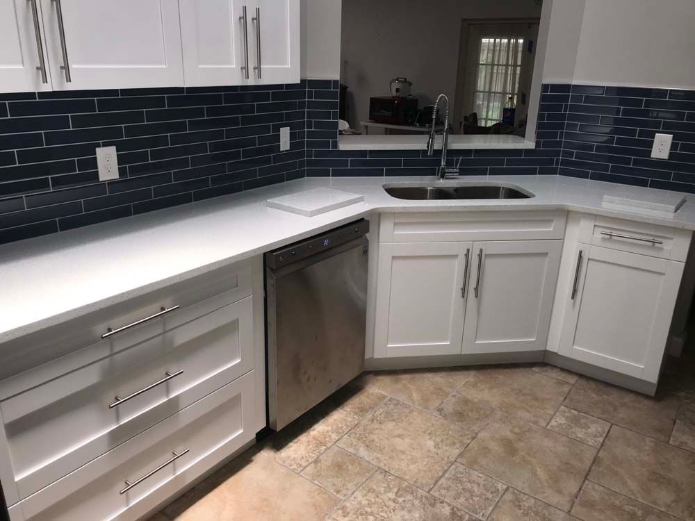 A kitchen with white cabinets , a sink , and a dishwasher.