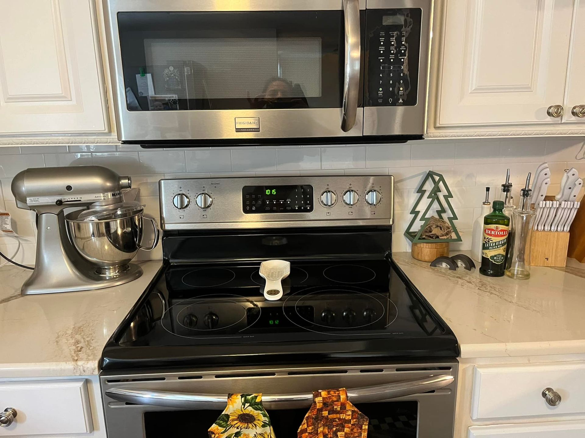 Kitchen with microwave, stove, mixer, and counters; Christmas tree decoration and olive oil bottle visible.