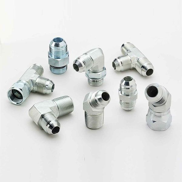 There are many different types of hydraulic fittings on a white surface.