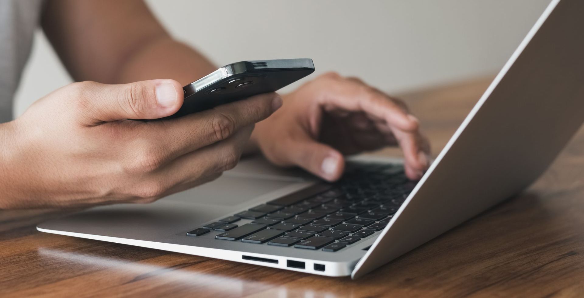 Une personne utilise un ordinateur portable tout en tenant un téléphone portable.