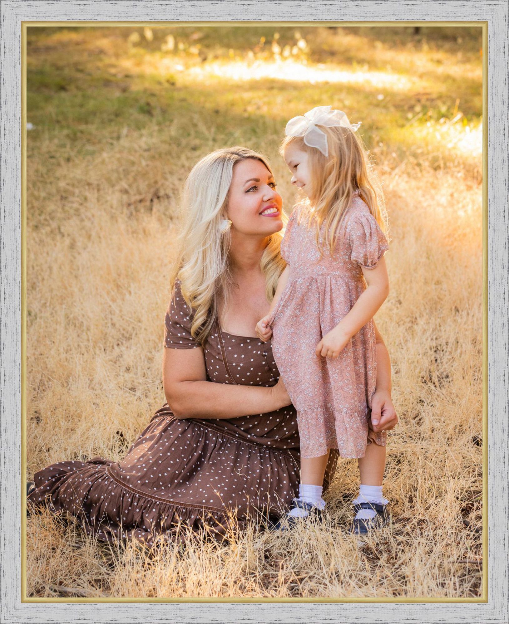 mom and daughter in dress in grass in the park