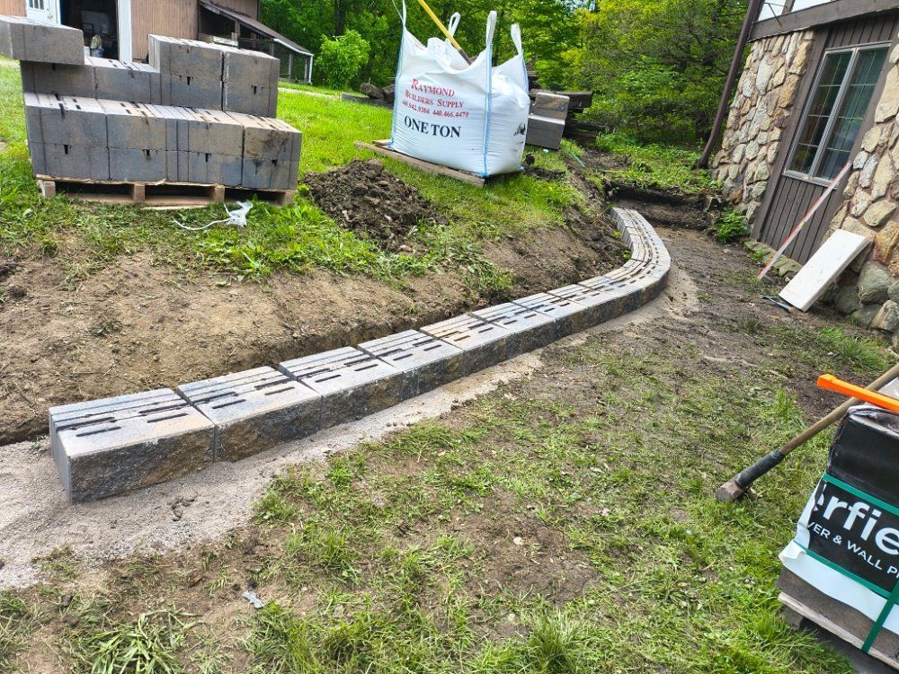 A brick wall is being built in a yard next to a house.