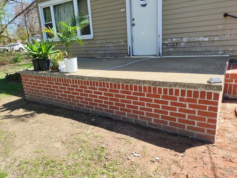 A brick wall is sitting in front of a house.