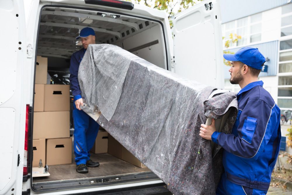 Two men are loading a couch into a van.
