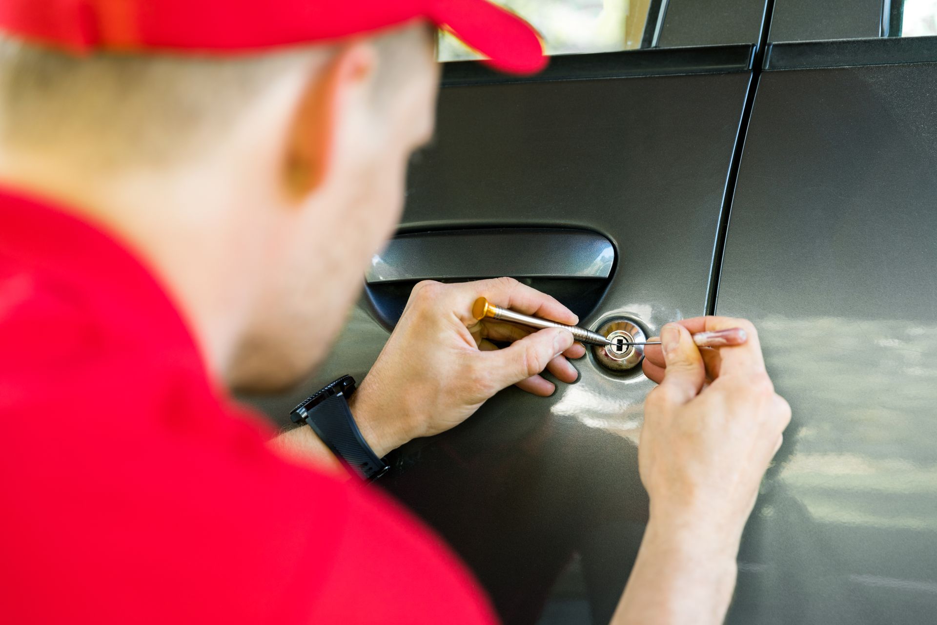 Locksmith unlocking car door with tool during car lockout emergency service