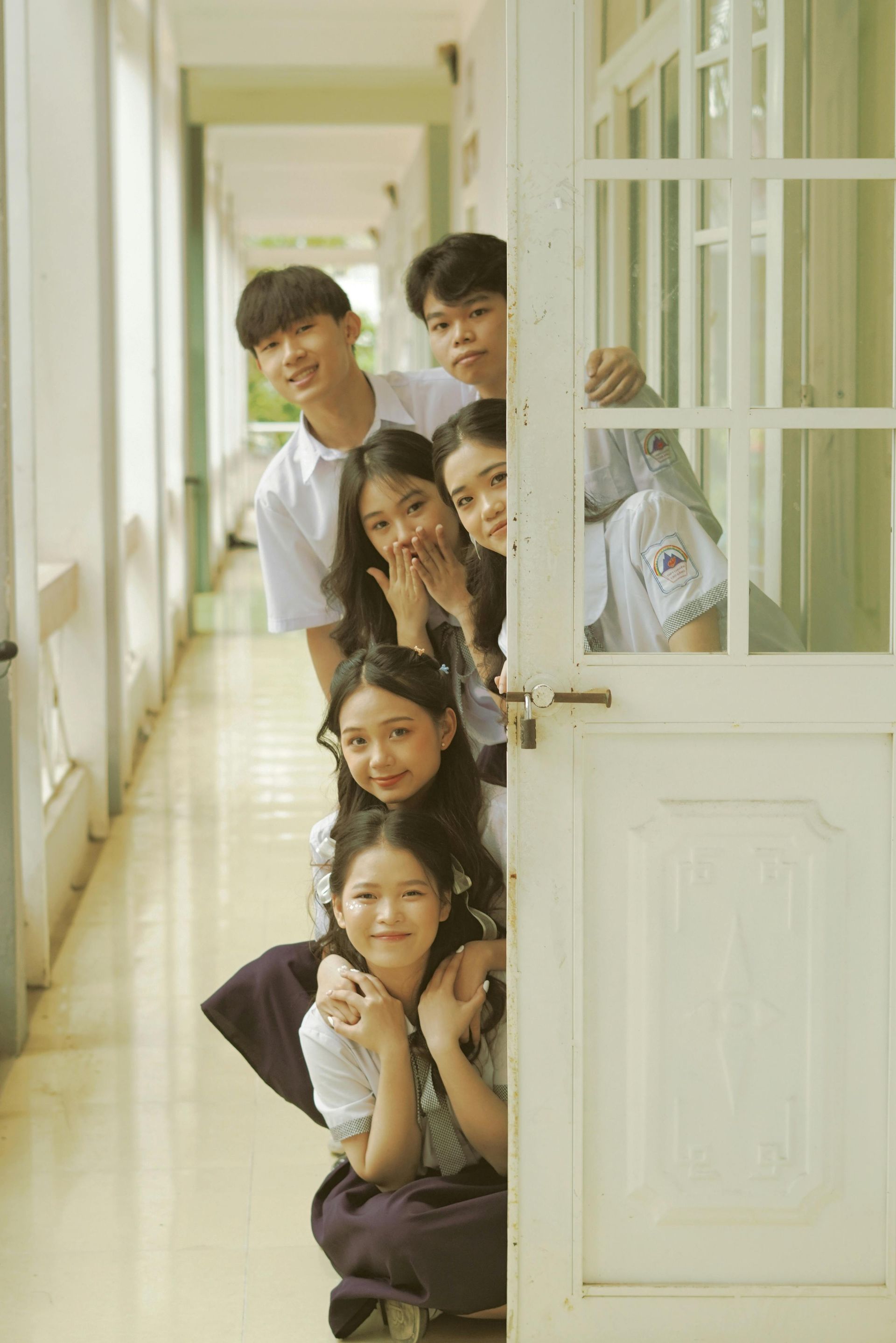 Group of cheerful students peeking from classroom door with excitement
