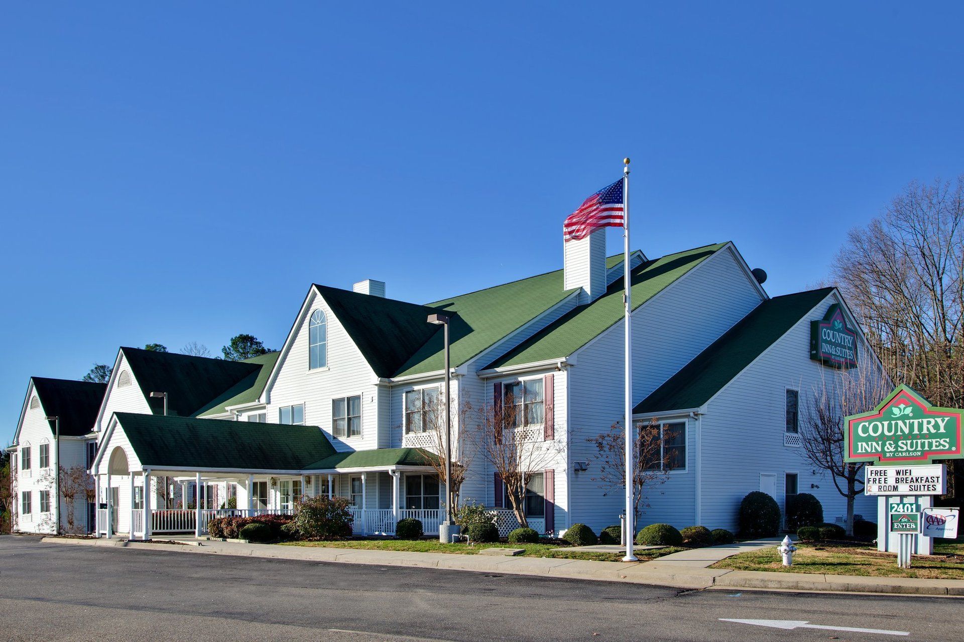 A large white house with a green roof and a sign that says country inn & suites