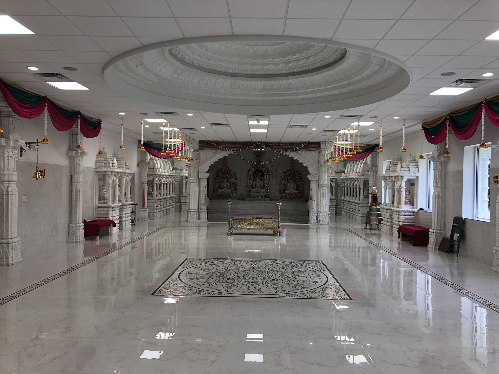 A large hallway in a building with a marble floor and a circular ceiling.