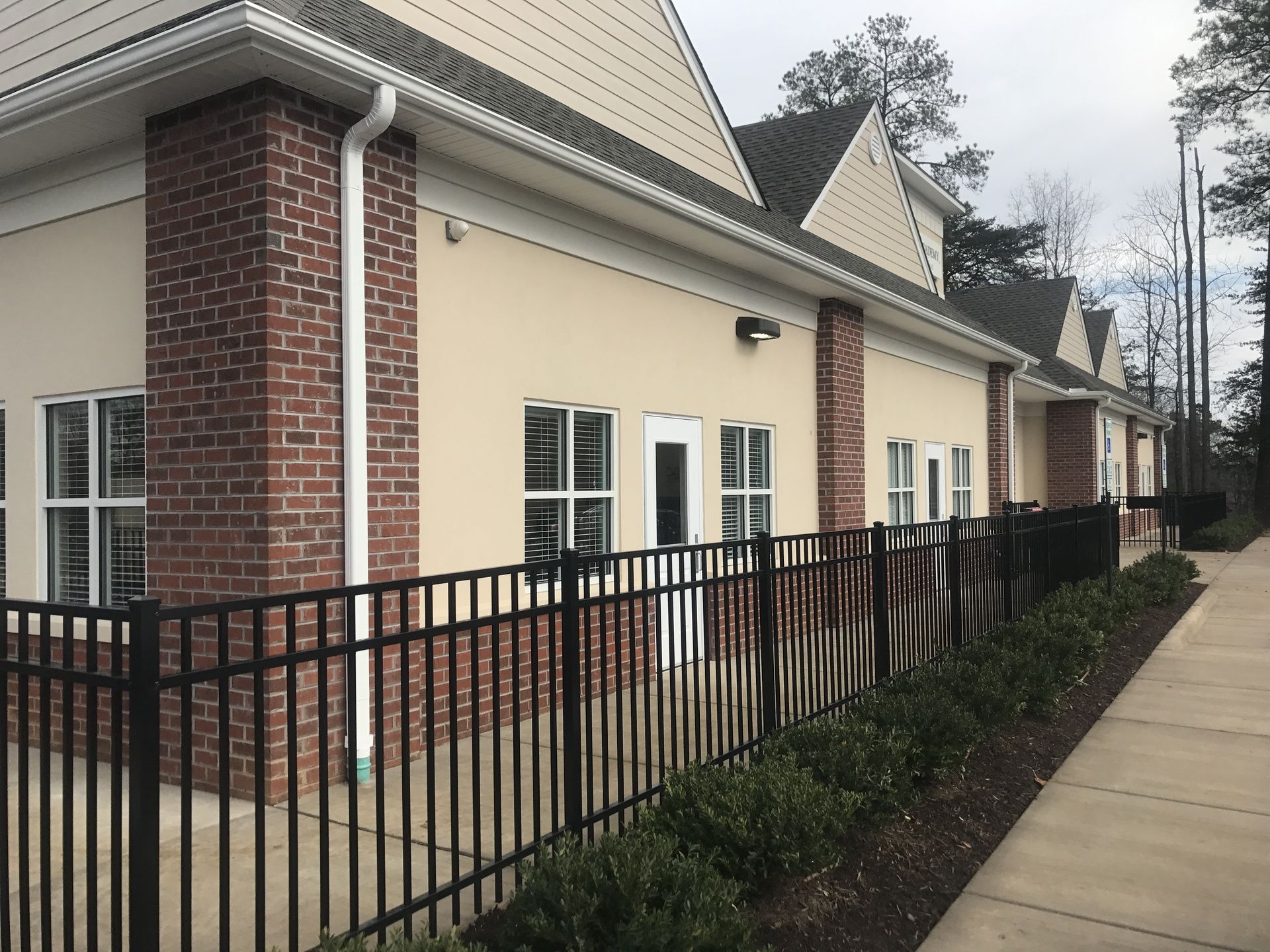 A brick building with a black fence around it